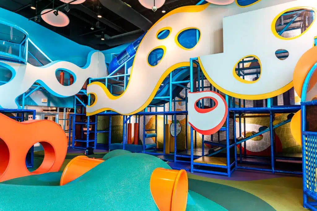 A bright (FREE) indoor playground in Dallas with a soft hill and orange tunnels located at Prestonwood Baptist Church.