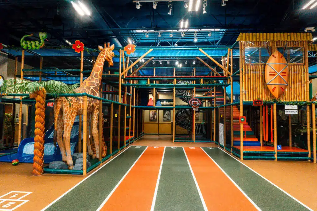 An indoor playground with a tall giraffe and racing lanes at Safari Run in Plano, Texas.