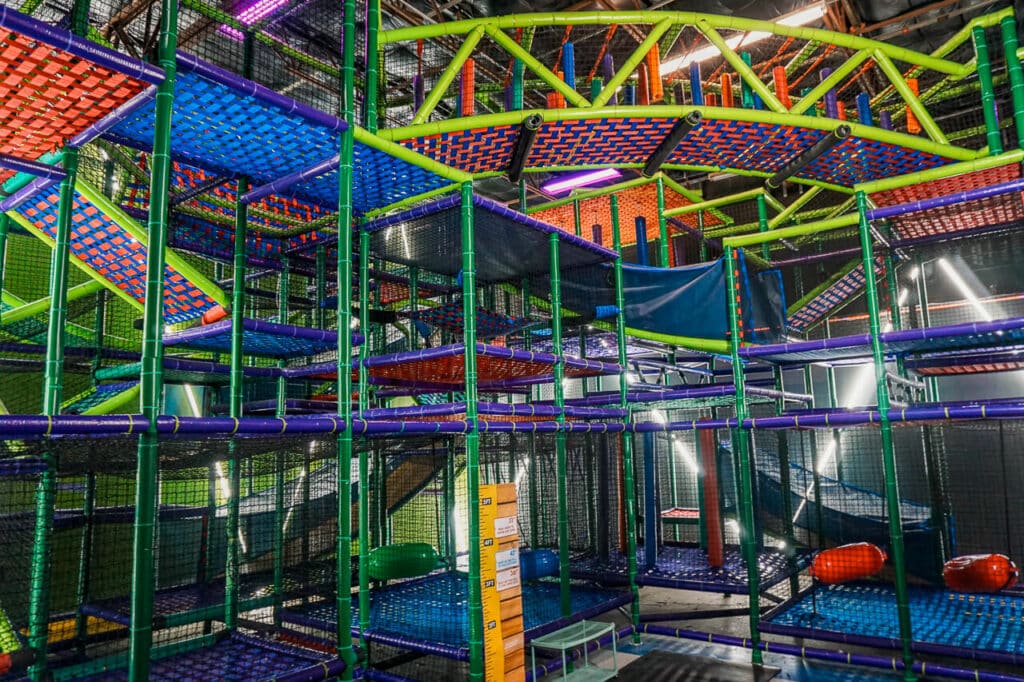 A colorful multi-level indoor playground in Dallas with a neon bridge at Shenaniganz.
