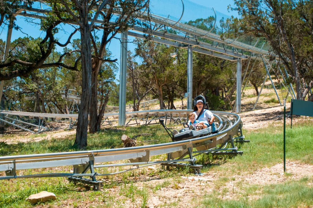 A mom and boy enjoying one of the best things to do in New Braunfels - riding Camp Fimfo's alpine coaster.