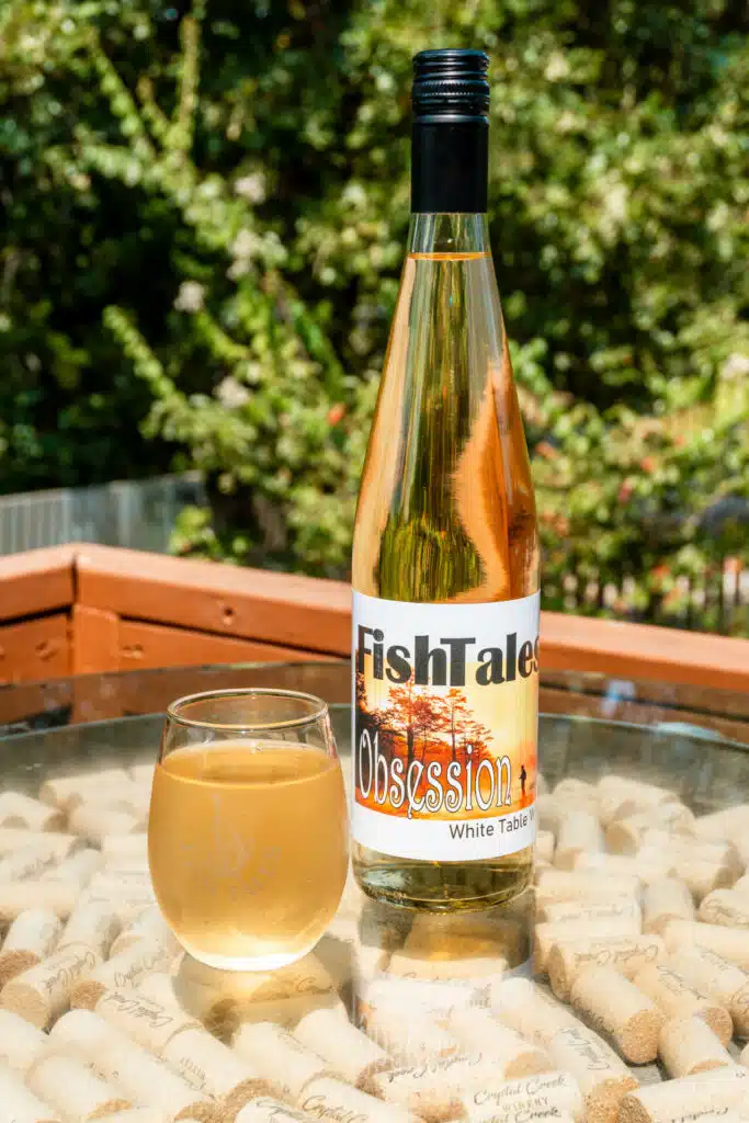 A glass of white wine alongside a bottle of wine from Fishtails Winery in Broken Bow.