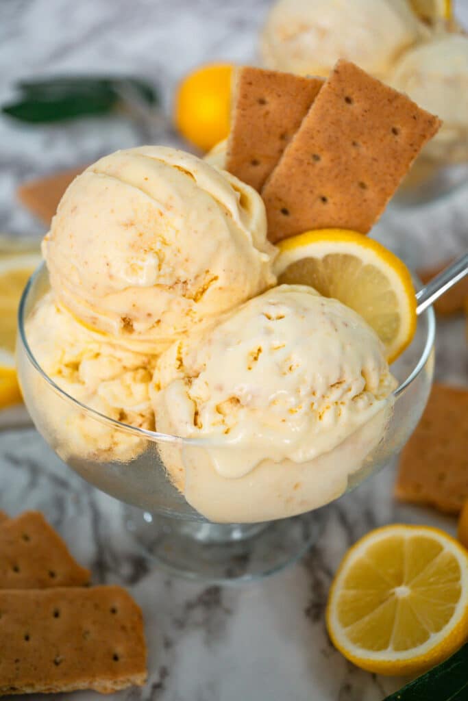 Three scoops of Lemon Pie Ice Cream with two graham crackers and a slice of lemon wedged in the ice cream.