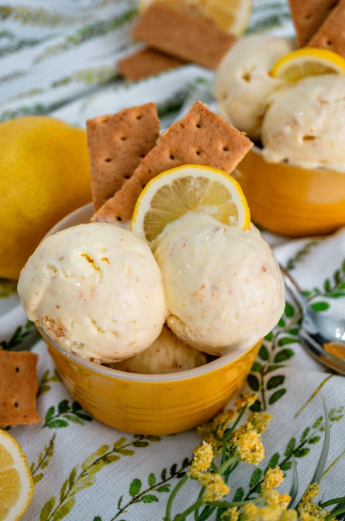 Two scoops of Lemon Pie Ice Cream with graham crackers and a lemon wedge on top.