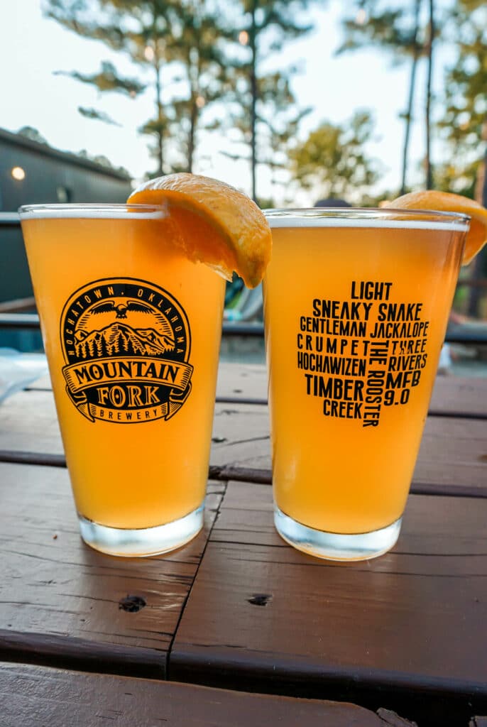 Two glasses of wheat beer with an orange slice from Mountain Fork Brewery.