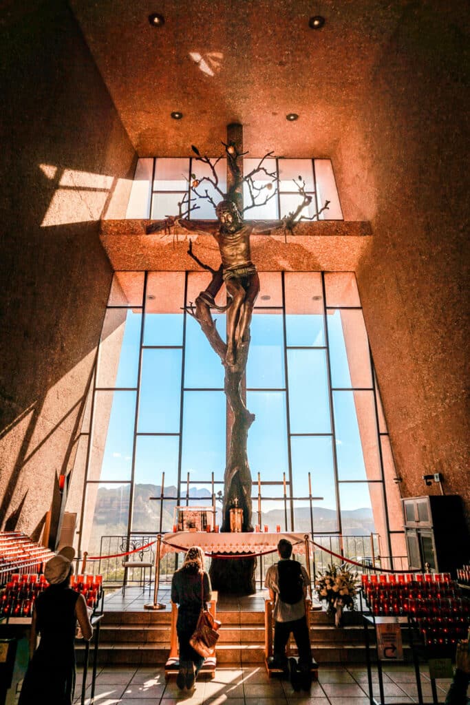 Two people kneeling and praying in front of Jesus inside the Chapel at the Holy Cross.