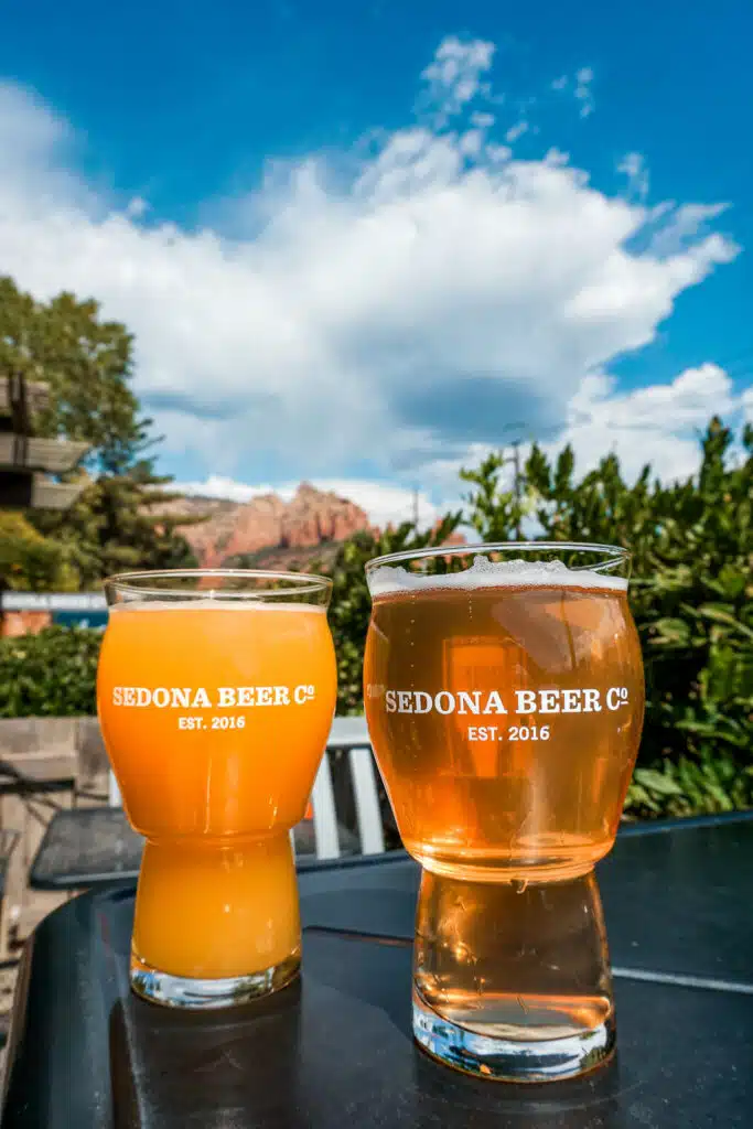 Two glasses of cold beer sitting on a table outside at Sedona Beer Company. 