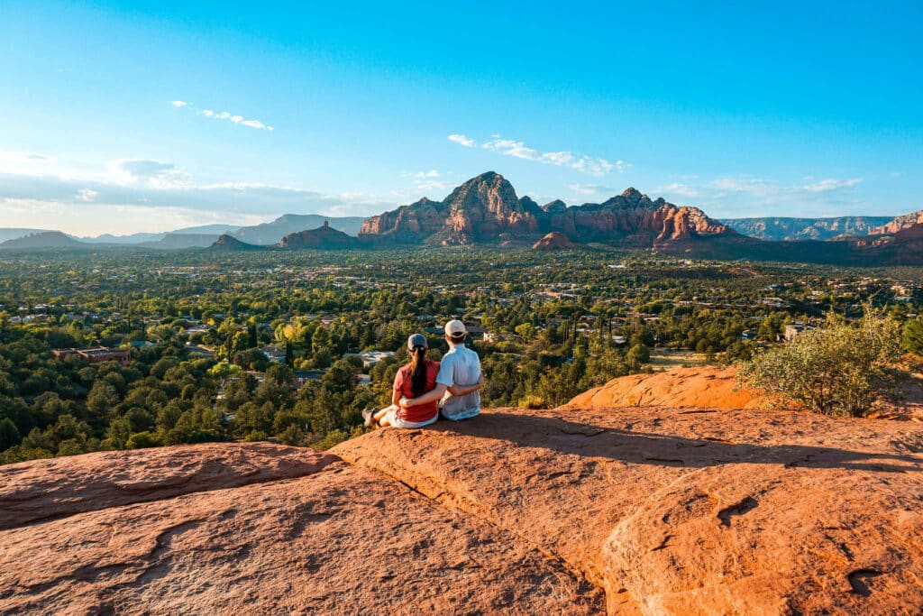 A couple sitting on the edge of the Airport Mesa summit enjoying sunset views of Sedona. 